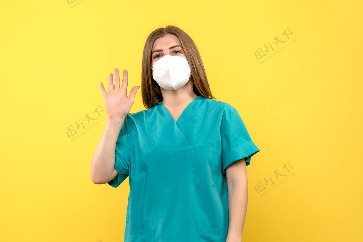 穿着正面图女医生戴着口罩在黄色地板上医院大流行病毒病毒肖像前面