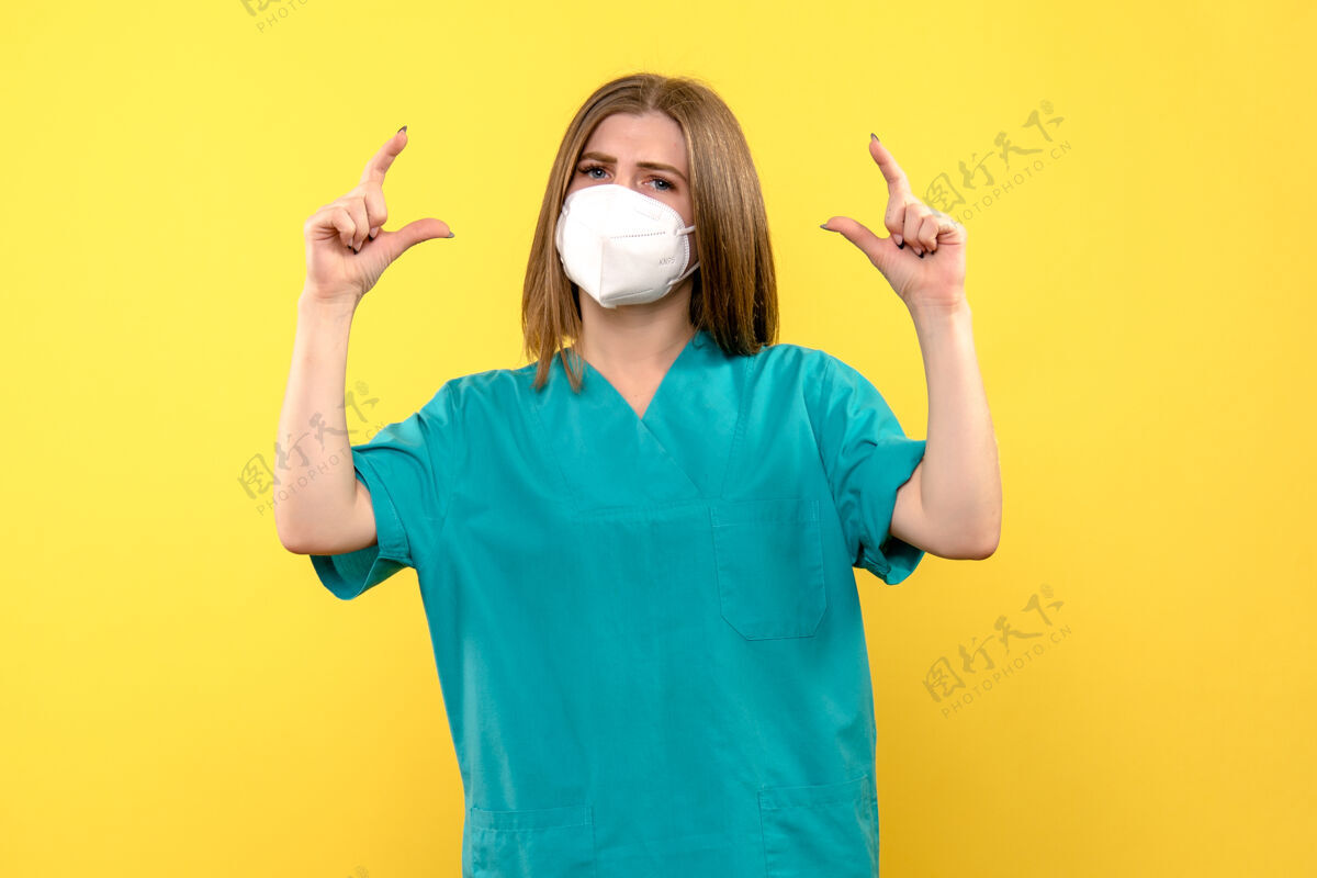 漂亮正面图黄色空间上戴着口罩的女医生一个视图肖像