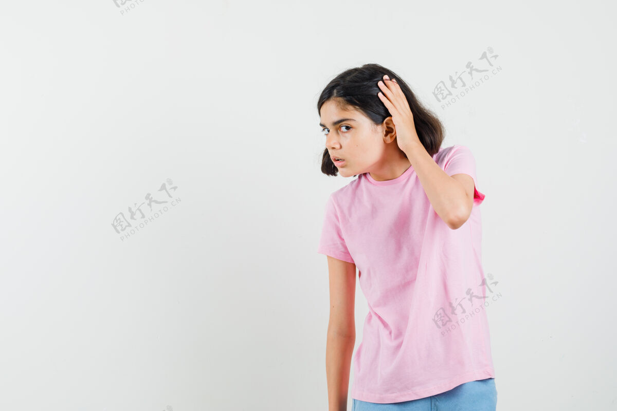 休闲小女孩手拉手靠近耳朵穿着粉色t恤 短裤 看起来很好奇前视图人美丽漂亮