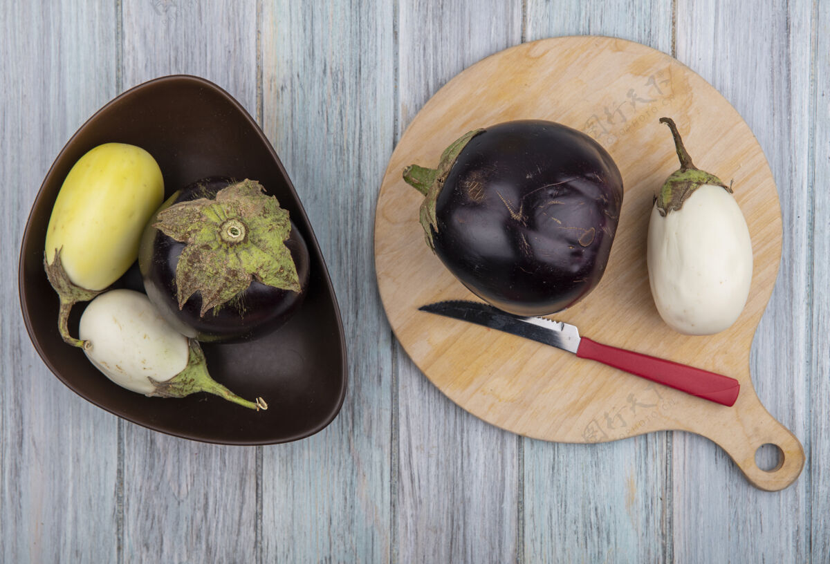 蔬菜在木制背景上 切菜板上和碗里放着刀的茄子俯视图板碗木头