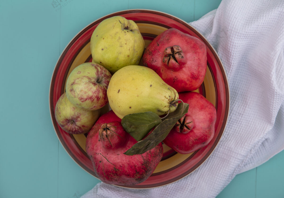 蓝色新鲜水果的俯视图 如石榴 木瓜和苹果 放在蓝色背景上的白布碗上水果石榴顶部