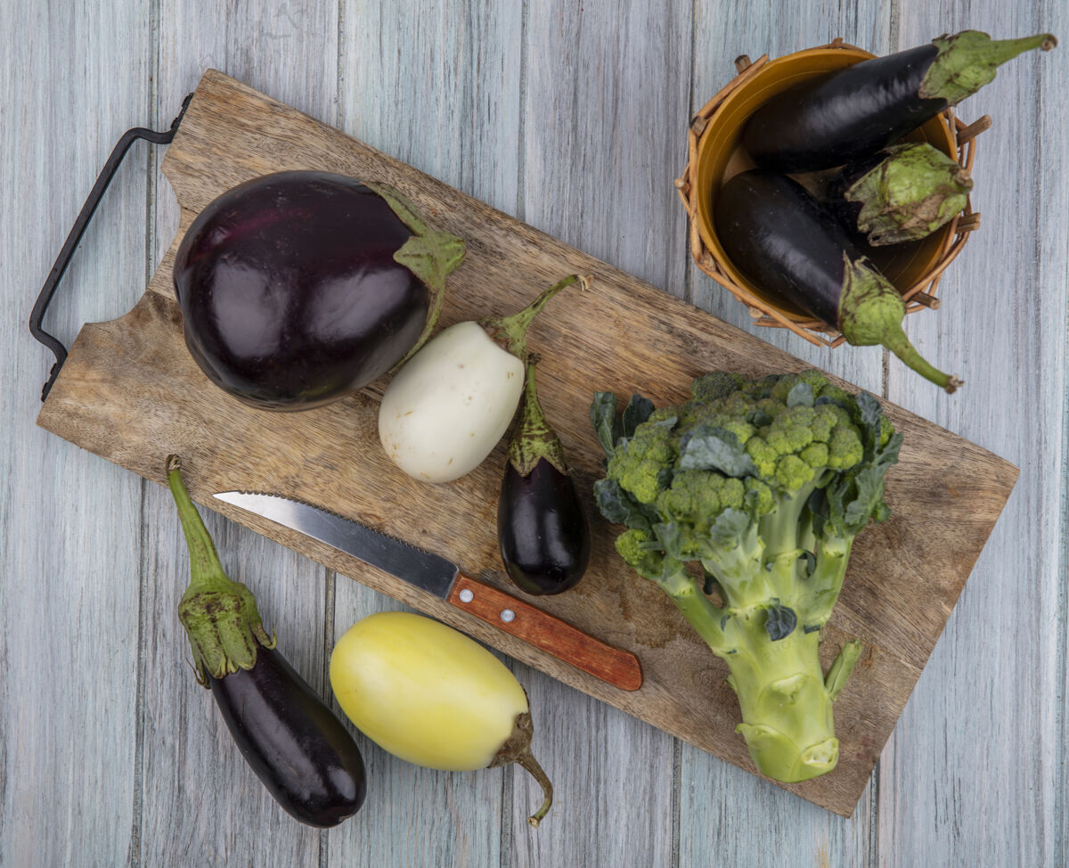 切蔬菜的俯视图 如茄子和西兰花 刀放在砧板上 篮子里和木制背景上板木头刀