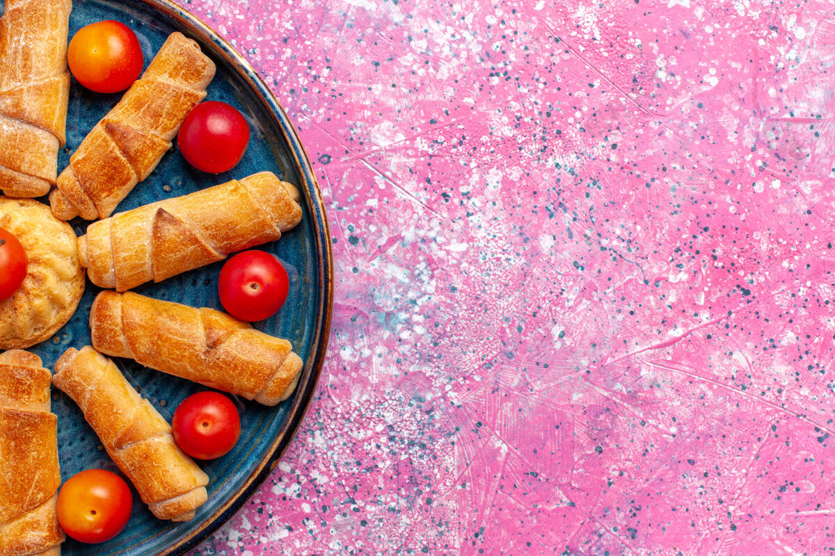 美味顶部近距离观看甜美美味的百吉饼烤糕点在托盘内与李子在粉红色的桌子上烤糕点蛋糕饼干甜甜的糖视图里面可食用的水果