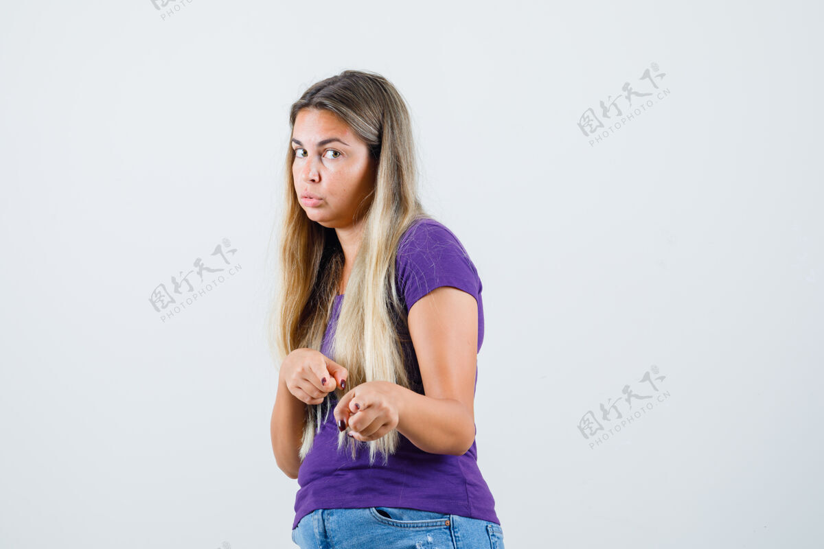 尖金发女郎指着前面穿着紫罗兰色的t恤 牛仔裤 看起来很可疑肖像牛仔裤漂亮