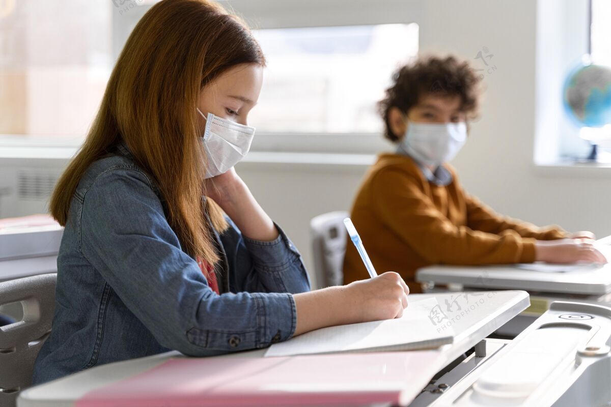 冠状病毒戴着医用口罩的孩子们在教室学习的侧视图学习教育水平