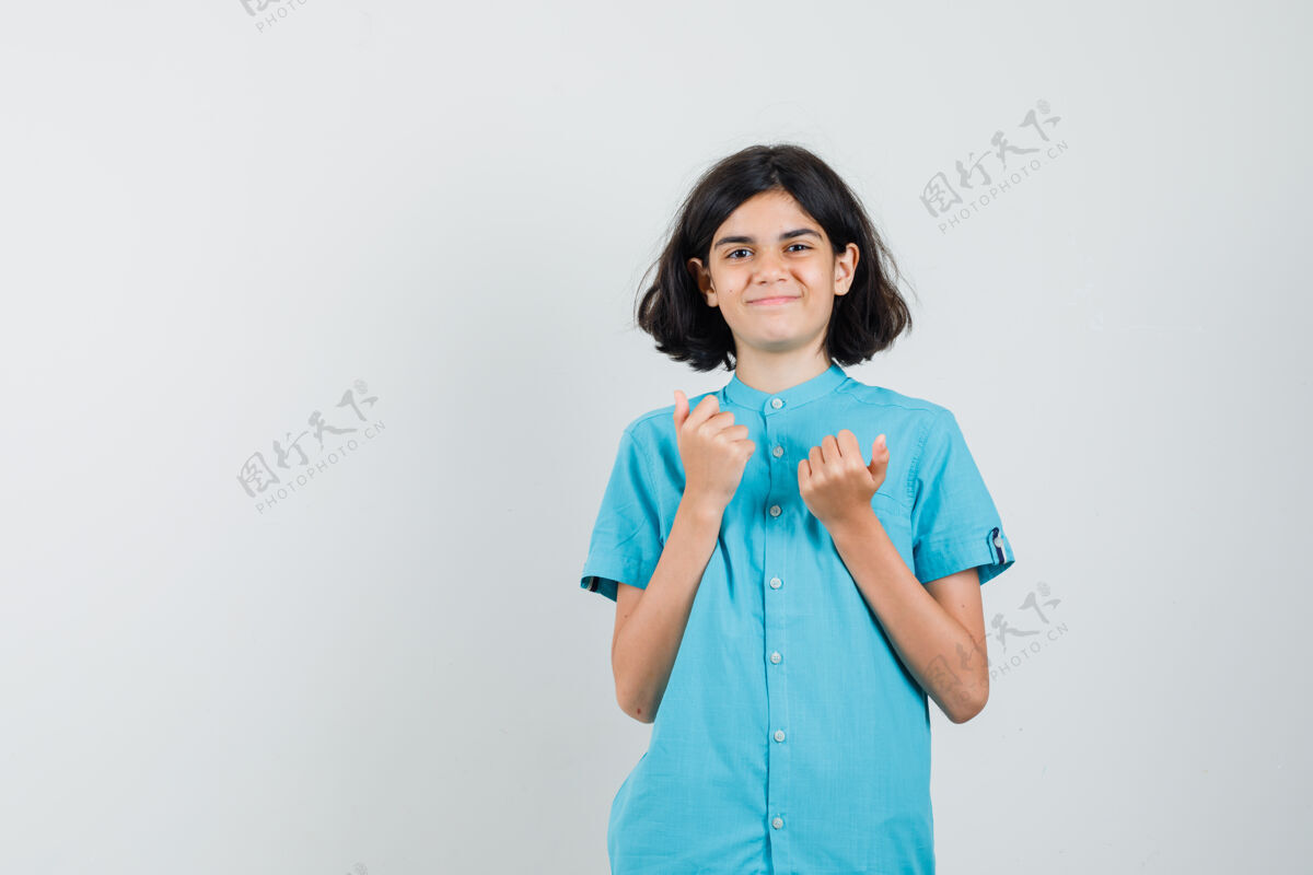 可爱十几岁的女孩犹豫不决 以显示拇指在蓝色衬衫 看起来复杂秀外观女性
