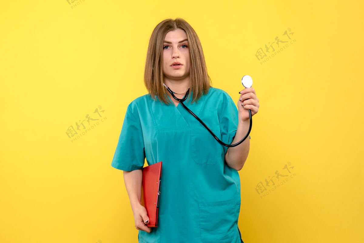 仪器黄色墙上带眼压计和锉刀的女医生的正视图医生前面血压计