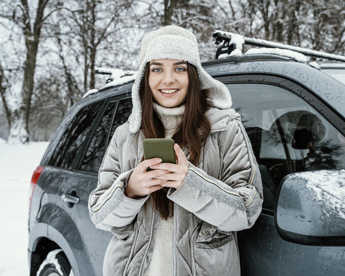 自然在公路旅行中使用智能手机的笑脸女人的前视图汽车冒险冬天