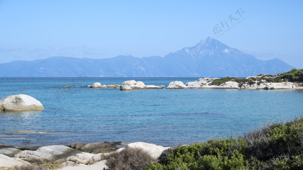 欧罗巴爱琴海海岸 水面上有岩石 远处有陆地 前景是绿色植物 蓝色的海水 希腊希腊山海滩