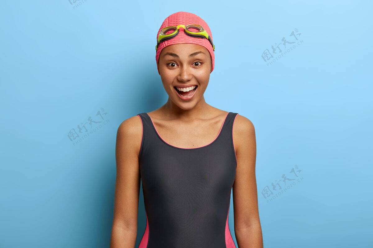 凝视积极的黑人女游泳教练穿着泳衣 泳衣和护目镜高兴爱好服装