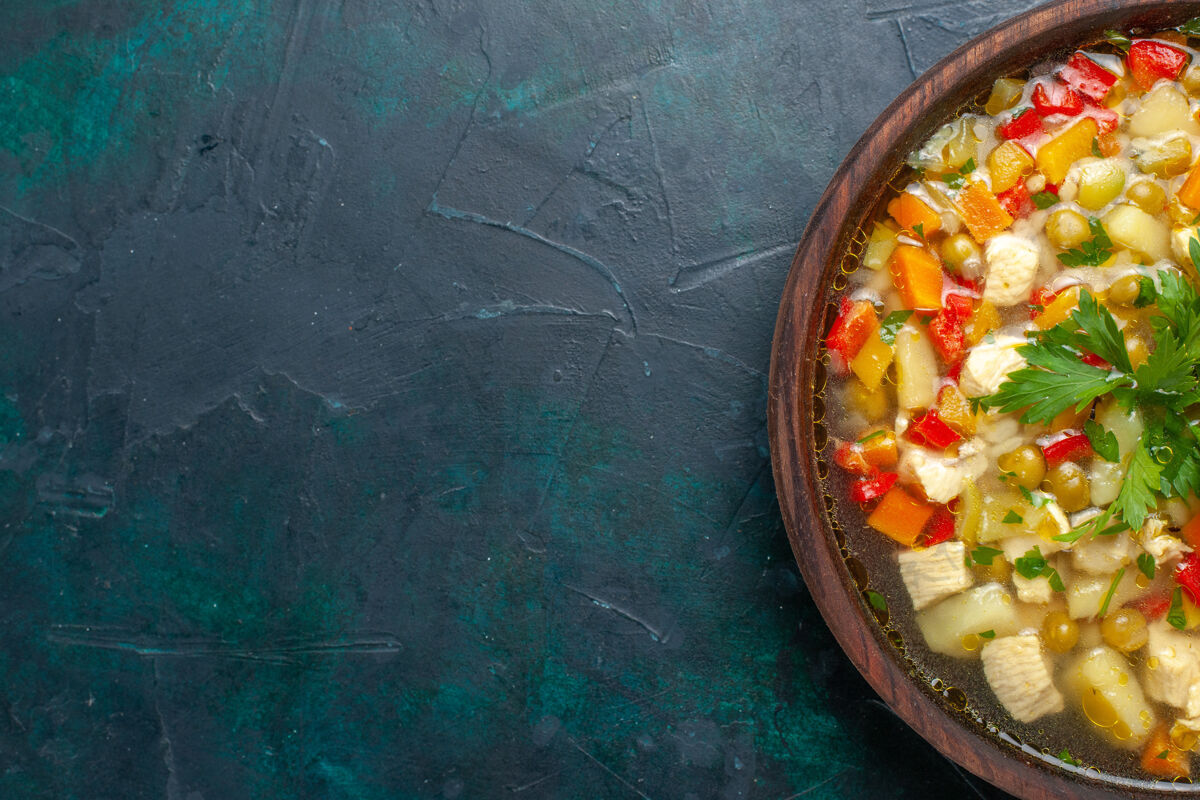视图俯瞰美味的蔬菜汤 里面有不同的配料 棕色的锅 深色的桌子上有汤 蔬菜酱 食物热的食物里面顶部生的
