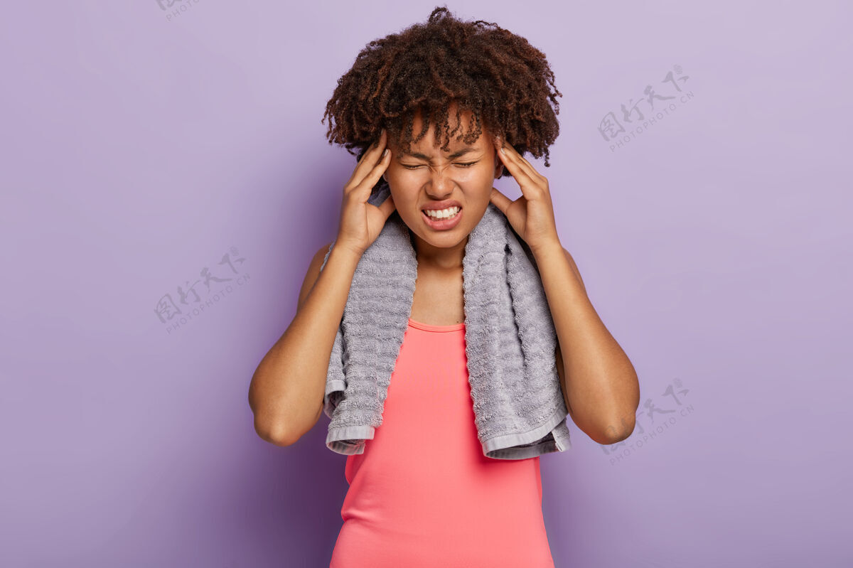 健身房疲惫疲惫的黑皮肤女人穿着粉色背心 摸太阳穴傻笑毛巾健身