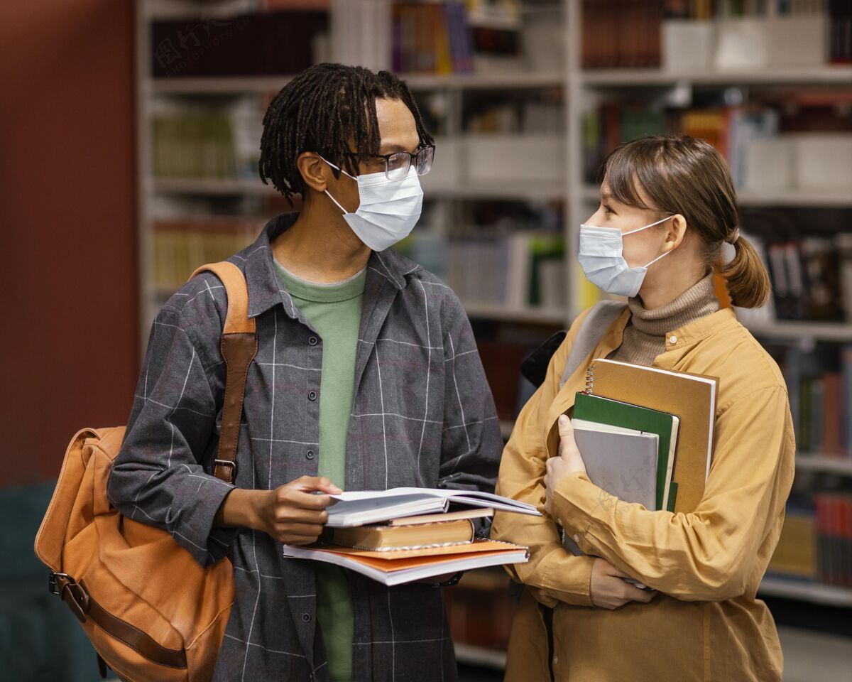 妇女学生们戴着医用口罩在图书馆里学生大学生活方式学校