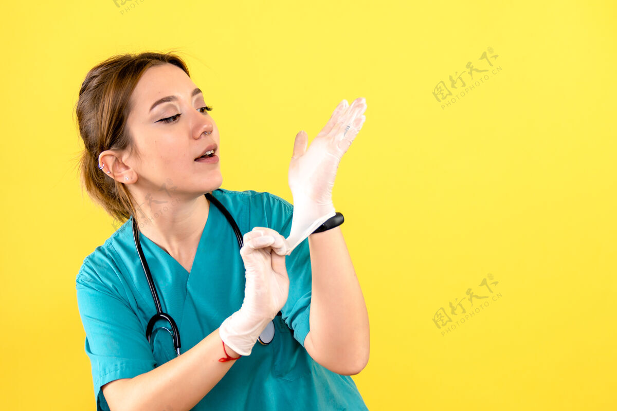 药黄色墙壁上戴手套的女兽医的正视图手套医院专业