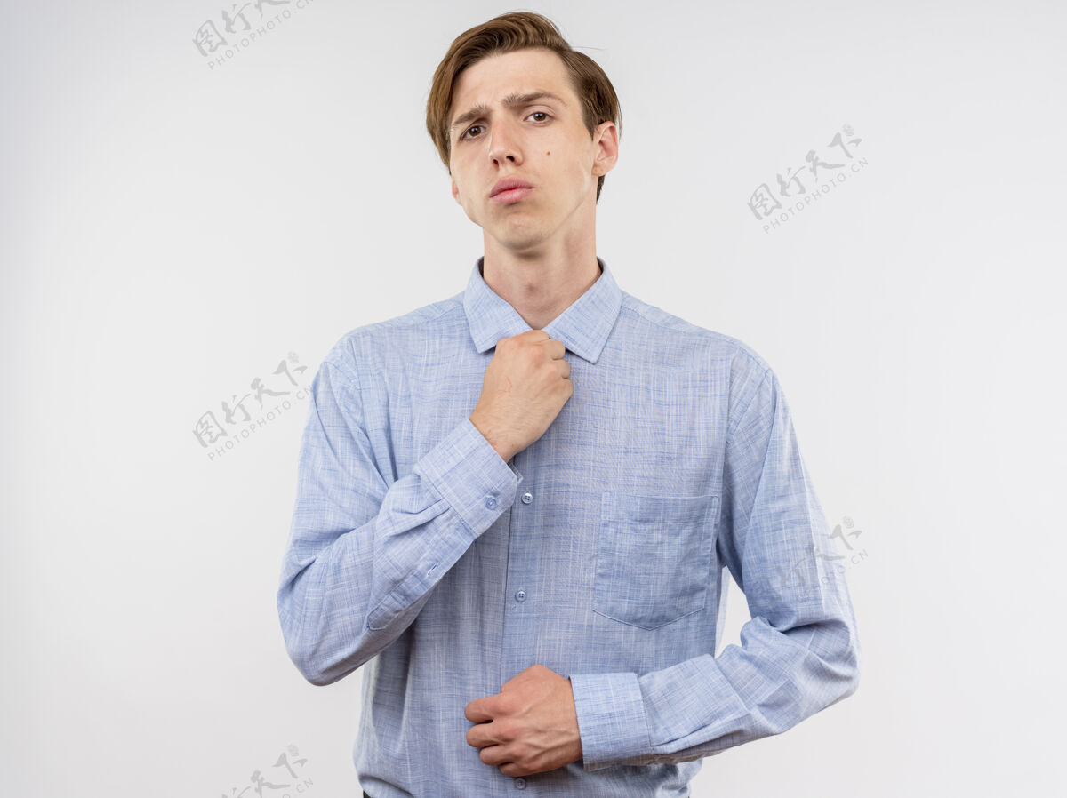 表情一个穿着蓝衬衫的年轻人站在白墙上 自信地修着衣领信心修复男人