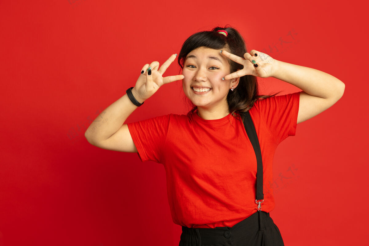 亚洲人亚洲青少年的肖像画独立于红色工作室背景美丽的深褐色女性模特 留着休闲的长发人类情感的概念 面部表情 销售 广告摆可爱的姿势工作专业女性