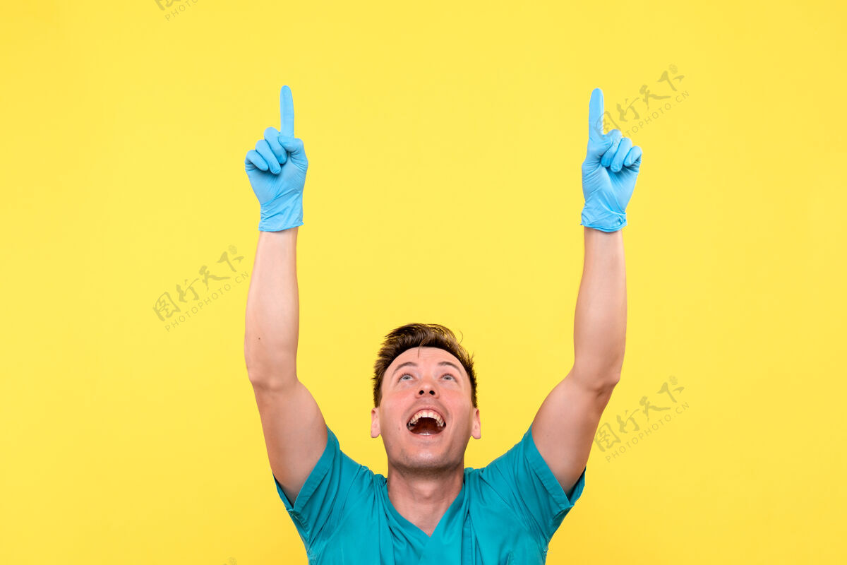 快乐黄墙上男医生戴着蓝手套摆姿势的正面图成人手套前面