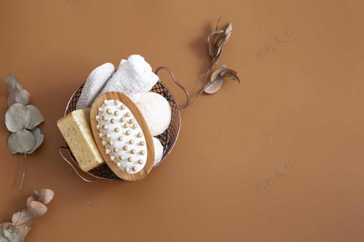 自然按摩刷 浴弹 肥皂和毛巾放在篮子里的棕色背景顶视图上木材化妆品浴弹