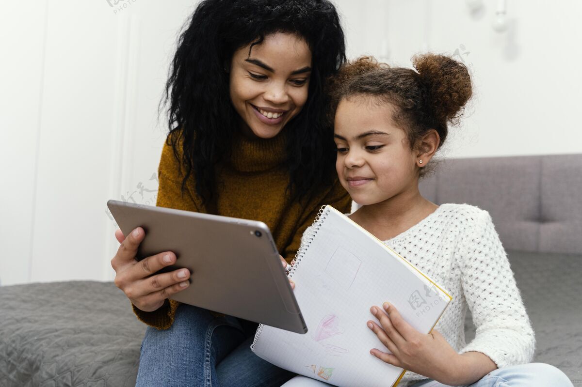 教育笑脸少女帮妹妹使用平板电脑上网上学在线青少年虚拟