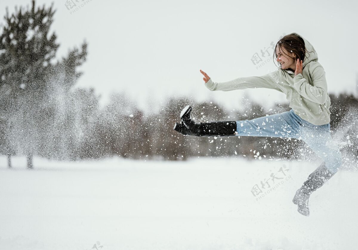 冬天女人在冬天在户外跳跃的侧视图欢呼姿势户外