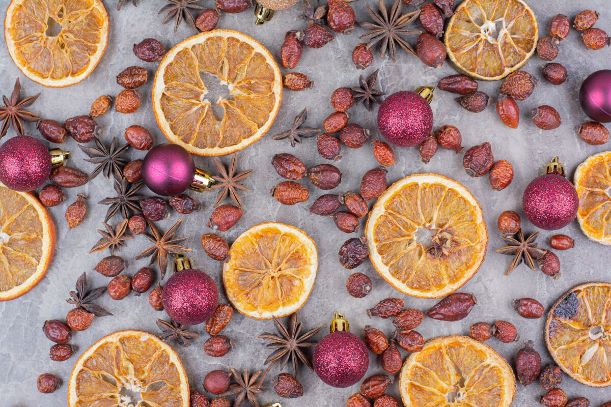 水果在石头表面有圣诞球和玫瑰果的干橘子干燥闪闪发光橘子