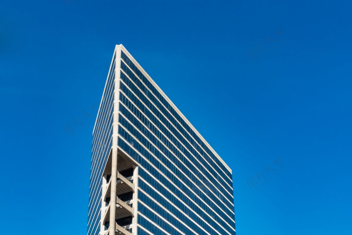 灯光在多云的蓝天下低角度拍摄的高玻璃建筑物反射建筑高