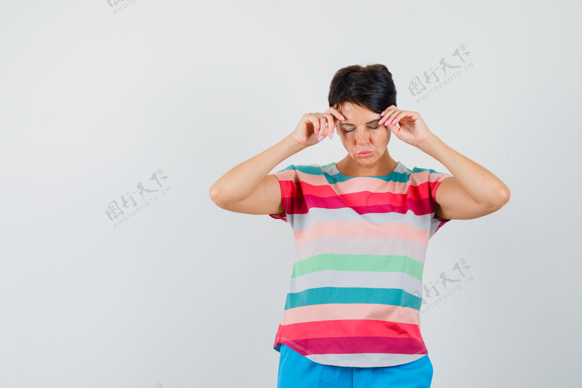 面罩女性穿着条纹t恤和裤子揉着她的太阳穴 看起来很疲惫前视图年轻人女人条纹