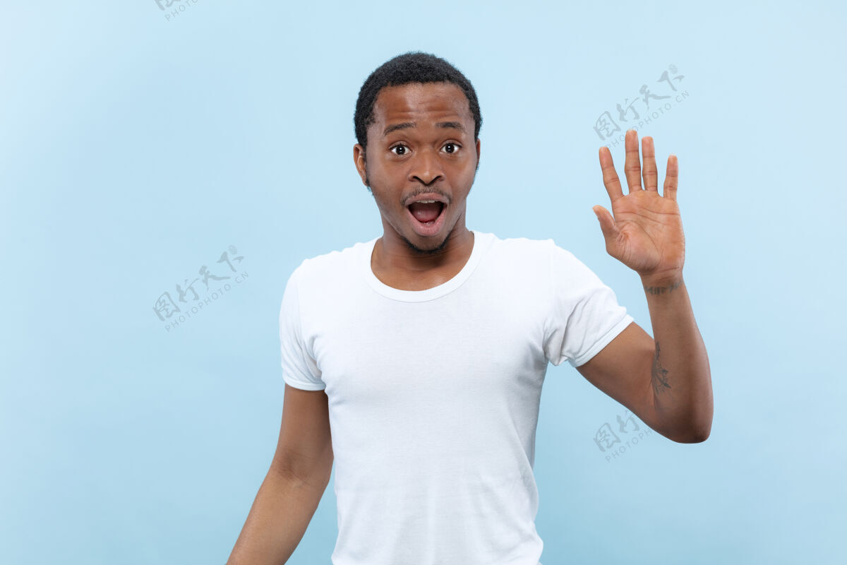 手半身特写 蓝色背景 身穿白衬衫的非洲裔美国年轻男子人类情感 面部表情 广告 销售理念会见某人 问候 邀请就业人肖像