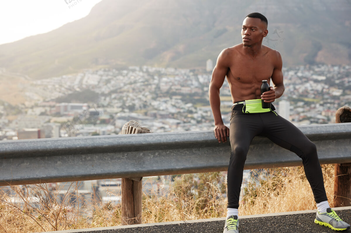 水合皮肤黝黑的农村男跑步者 喝水 享受休息 在炎热的夏天进行积极的体育锻炼 在路标旁休息 从喝落基山脉中获得能量高速公路山地激烈