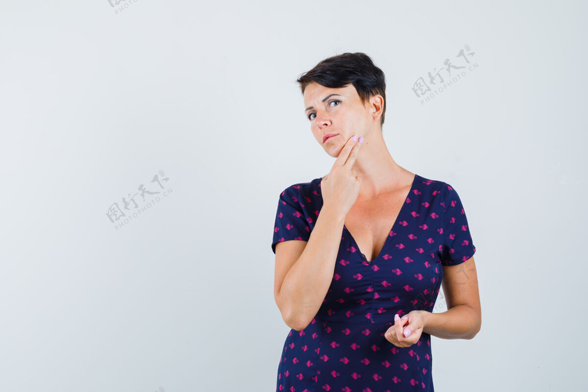 成人一个黑发女人穿着紫色和红色图案的裙子检查她的脸 看起来很专注前视图年轻格子漂亮