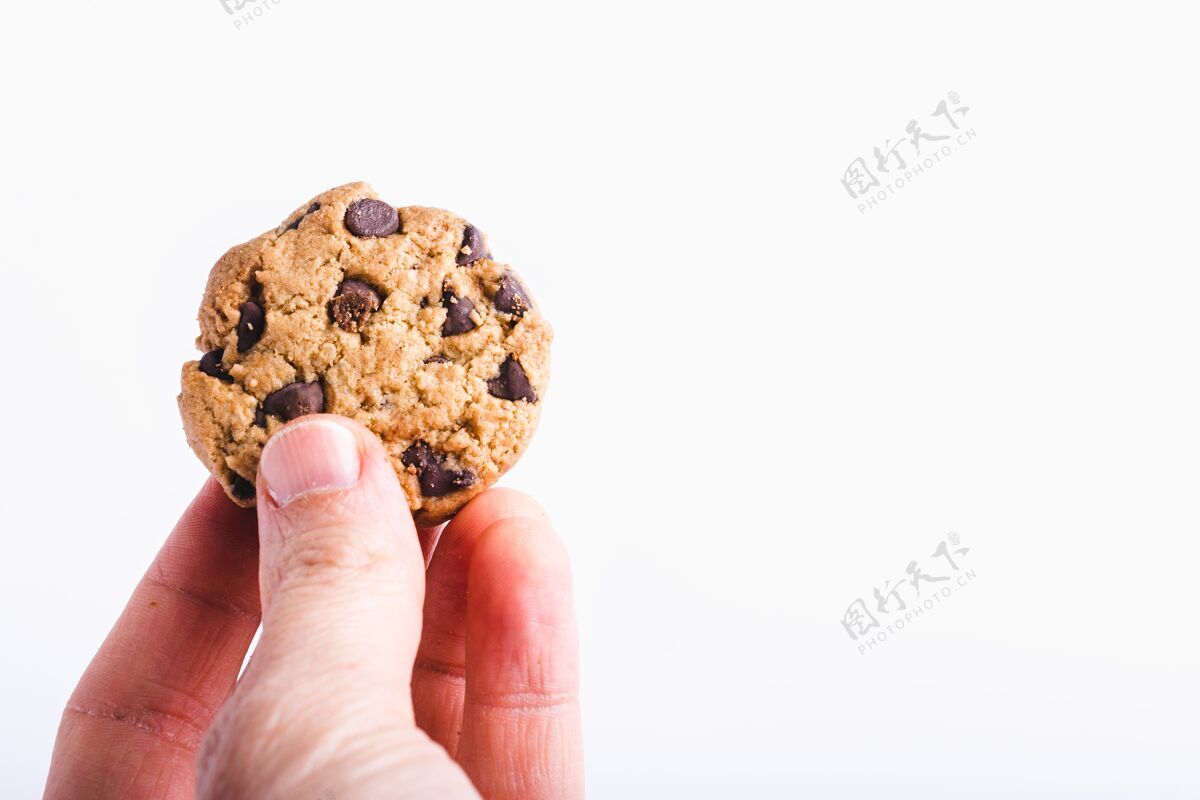 甜点一个拿着巧克力饼干的人的特写镜头被隔离在白色上热的吃持有