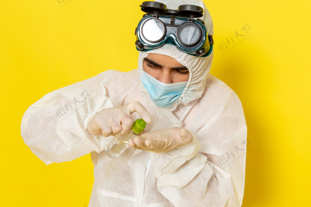 前面正面图穿着特殊防护服的男性科学工作者拿着喷雾剂在黄色的表面上使用它特殊男性举行