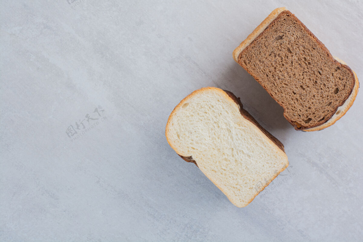 新鲜新鲜的白色和棕色面包片放在大理石背景上烘焙面包房美味
