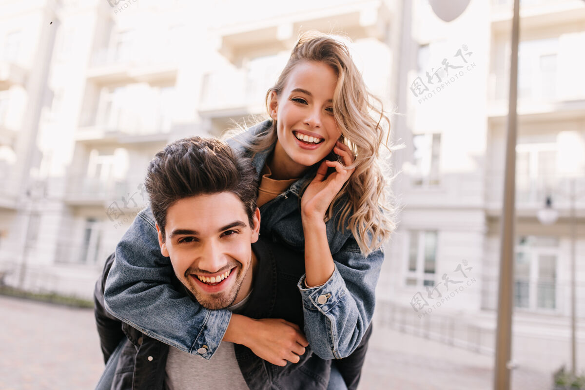 肖像穿着牛仔夹克的女孩拥抱男朋友微笑的白人夫妇在街上合影人乐趣关系