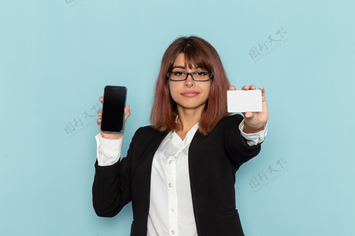 西装正面图：身着正装的女上班族拿着电话和白卡在蓝色的表面上手持工作酒精