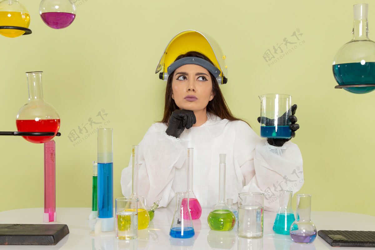 医生前视图穿着特殊防护服的女化学家在绿色表面上处理溶液溶液化学家实验室外套
