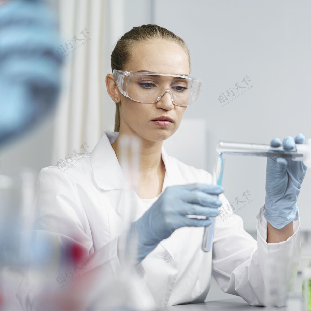 广场实验室里的女研究员的正视图 带着试管和安全眼镜女人实验室技术员专家