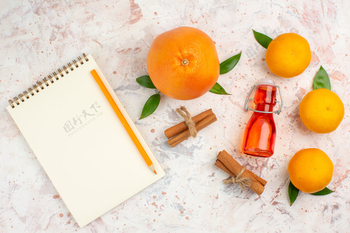 笔记本顶视图新鲜橘子肉桂棒橘子瓶铅笔笔记本在明亮的表面新鲜柑橘脐橙铅笔