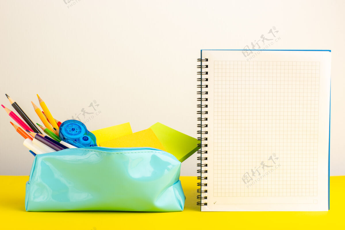 彩色正面图黄色书桌上的蓝色笔盒内有不同颜色的铅笔和抄写本书桌抄写本正面