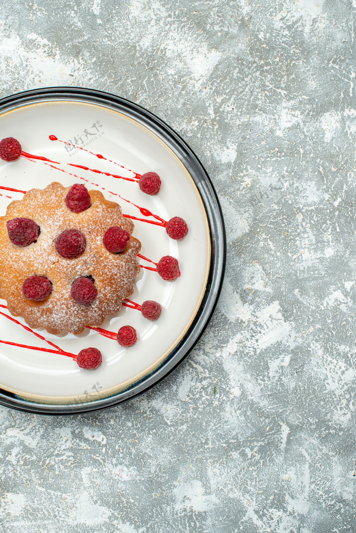 椭圆形俯瞰浆果蛋糕上的白色椭圆形盘子上的灰色表面食物照片视野草莓顶部