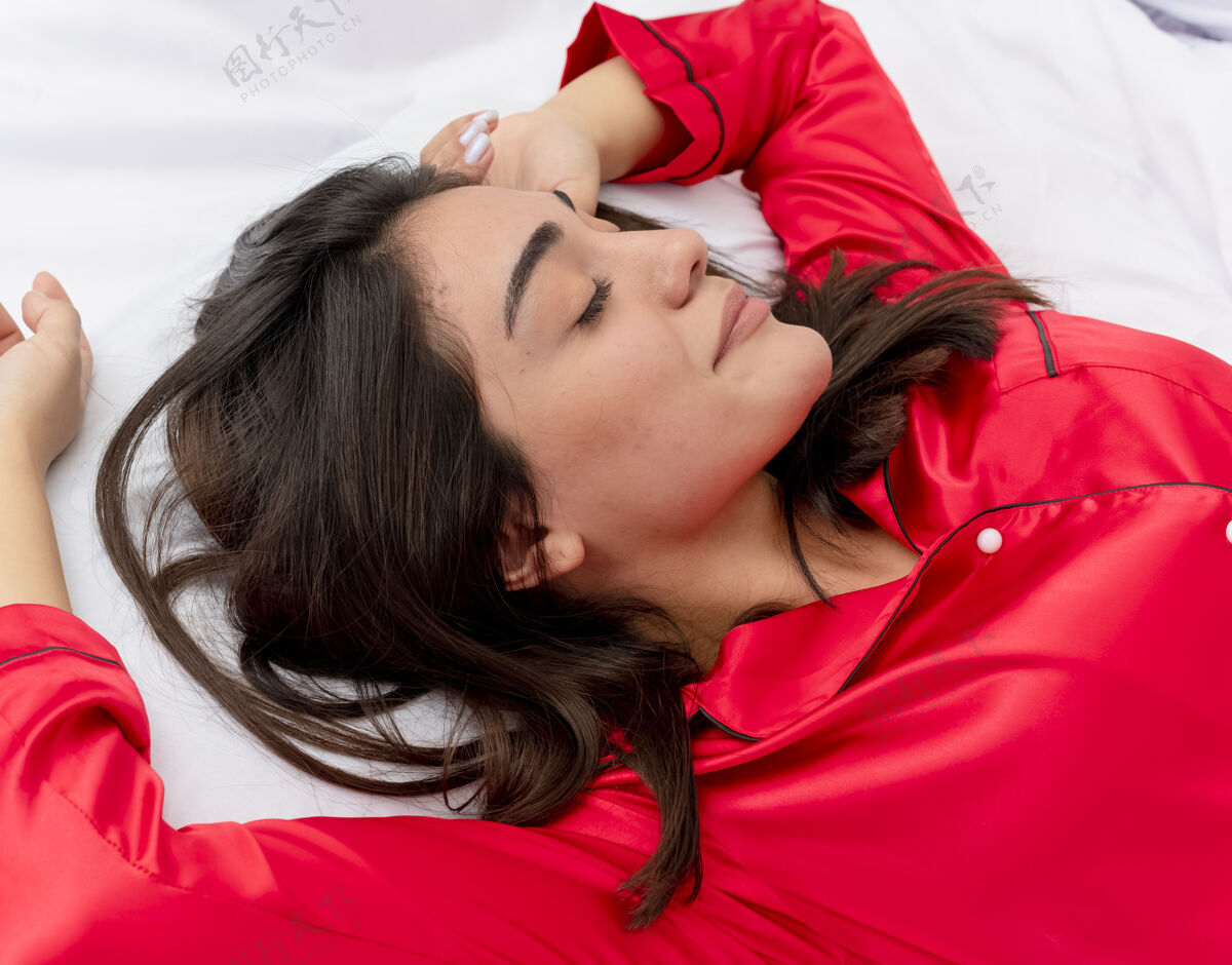 躺着穿着红色睡衣在床上放松的年轻美女美丽年轻女人