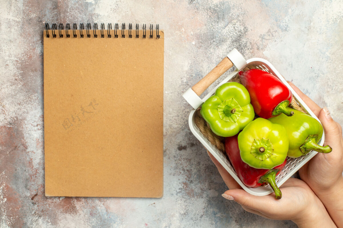 吃苹果顶视图绿色和红色的辣椒在塑料篮在女性手中一个裸体表面记事本番茄顶部蔬菜