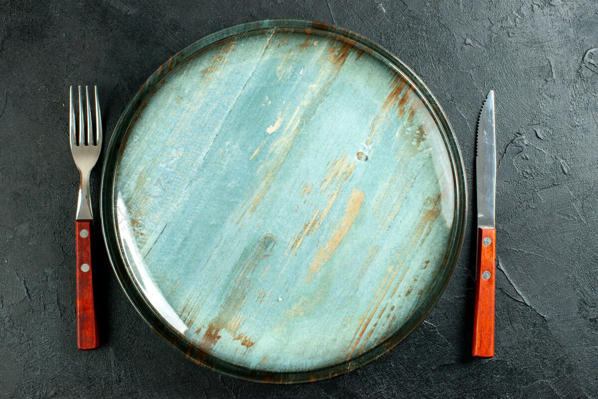 碗顶视图圆盘刀和叉子在黑暗的表面锅盘子托盘