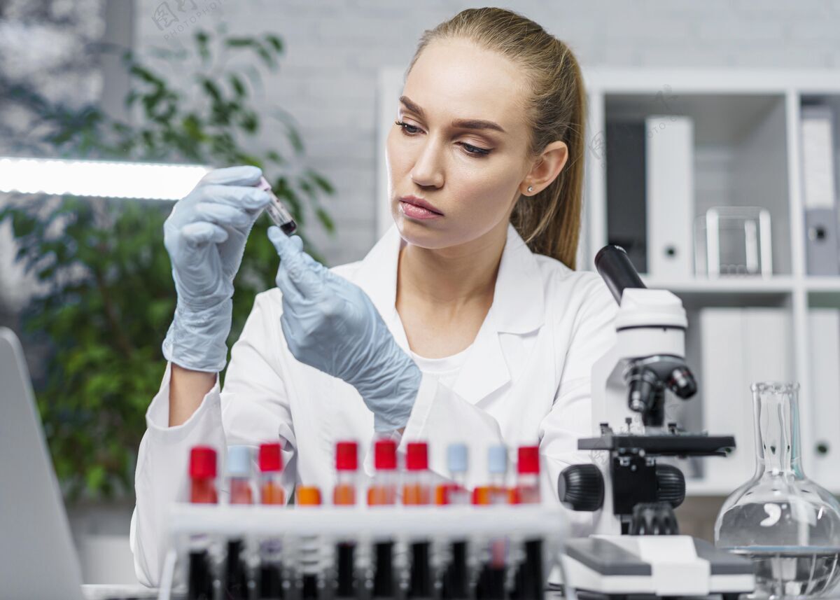 科学家女研究员在实验室里拿着试管和显微镜的正视图女技术员实验室技术员