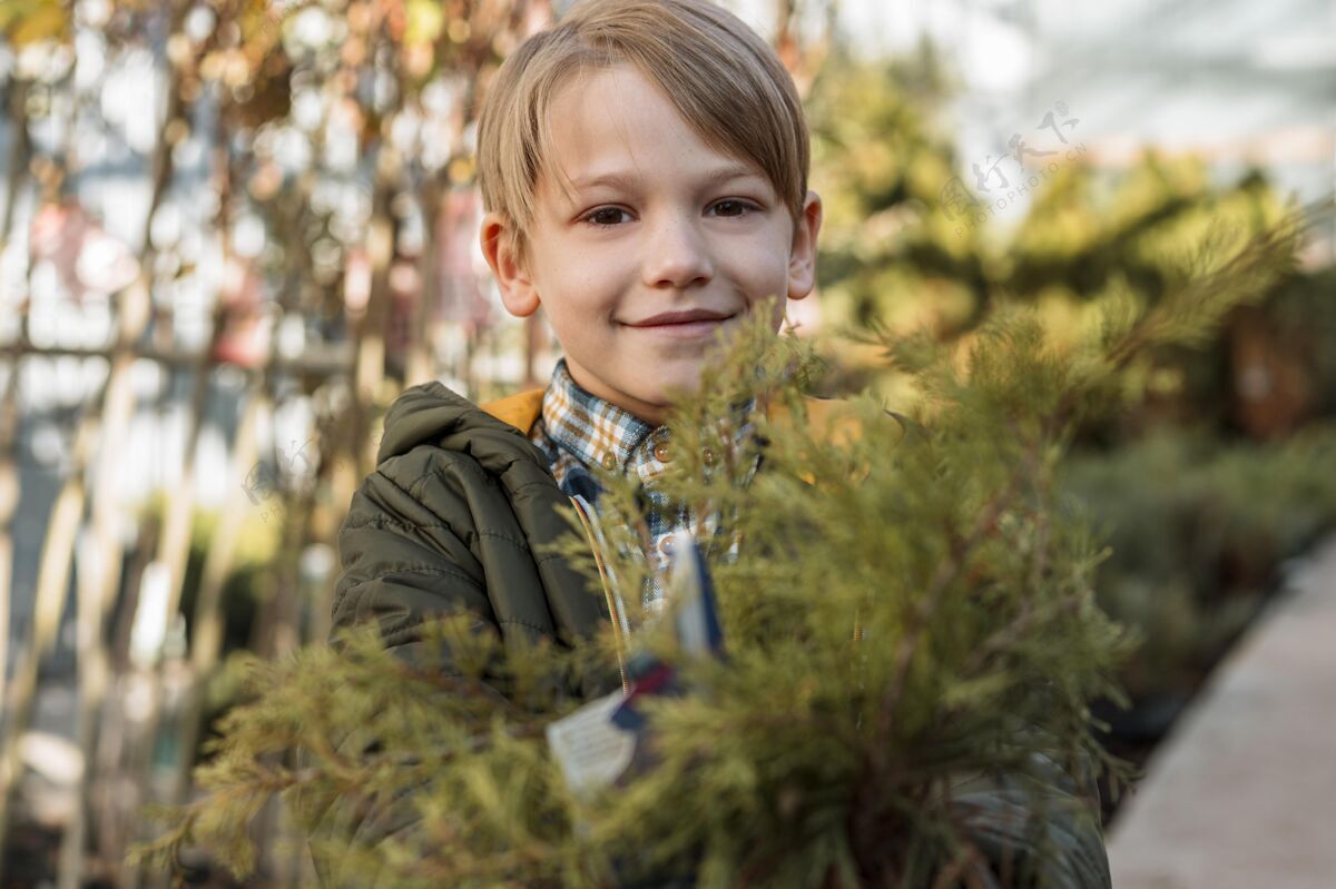 园艺笑脸男孩拿着一棵小树在锅里种植植物农业