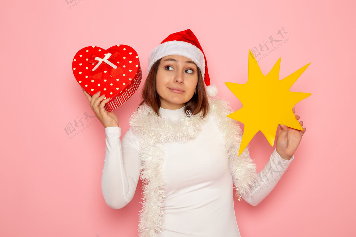 颜色正面图年轻女性手持黄色的身影 呈现在粉色墙壁上雪地圣诞色节日新年时尚年轻女性风景贵族