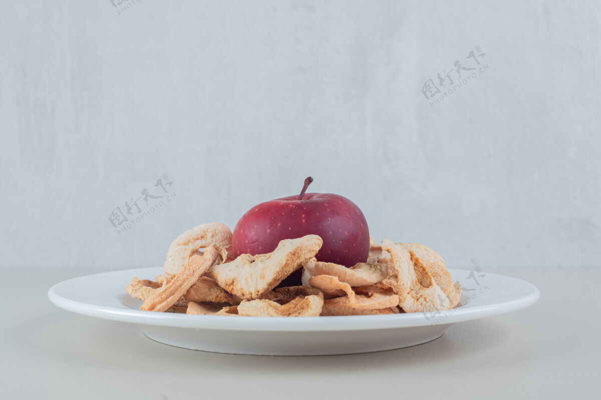 烹饪一个白色的盘子里装满了干苹果和一个完整的苹果团体苹果健康