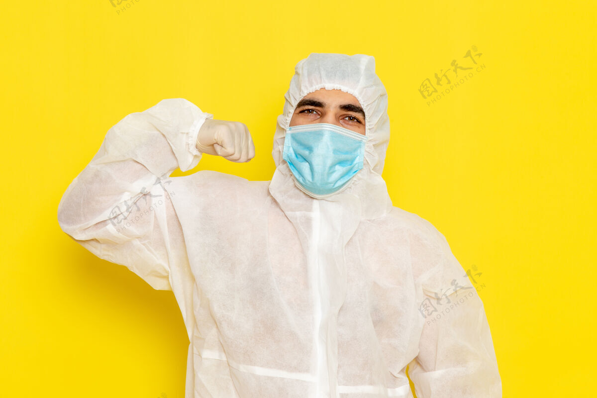 护士男性科学工作者的正面图 穿着特殊的白色防护服 戴着面罩 在浅黄色的办公桌上 科学工作者的科学化学颜色危险浅黄色医学特殊