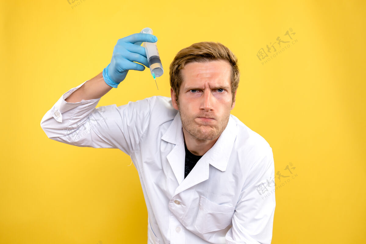 注射正面图男医生拿着黄色背景上的大针头医学病毒病毒帅哥成人