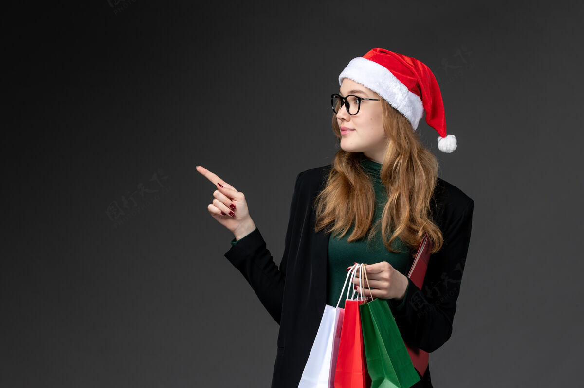 漂亮正面图：年轻女性 黑色墙壁上有包装礼品新年礼物圣诞节服装风景